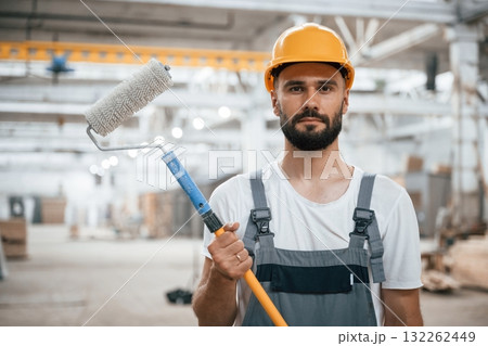 With brush for coloring. Industrial worker in wooden warehouse With brush for coloring. Industrial worker in wooden warehouse 132262449