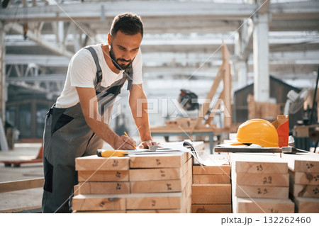 Bunch of paper documents and plans. Industrial worker in wooden warehouse Bunch of paper documents and plans. Industrial worker in wooden warehouse 132262460