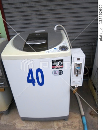White Coin Operated Washing Machine with a Blue Number 40 in a Laundry Area 132262699