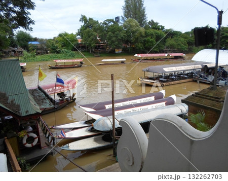 Fleet of Mae Ping River Cruise Boats Moored Along a Lush Riverside Scene Fleet of Mae Ping River Cruise Boats Moored Along a Lush Riverside Scene 132262703
