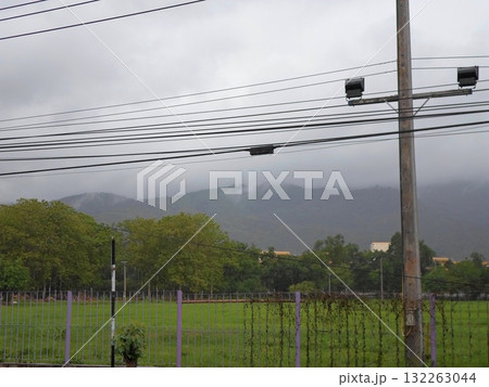 Misty Field with Purple Fencing and Distant Mountains Under Cloudy Skies 132263044