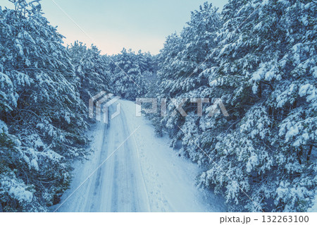 Nature winter background. View from above of snowy forest and country road. Pine trees are covered with snow. Winter nature. Christmas background 132263100