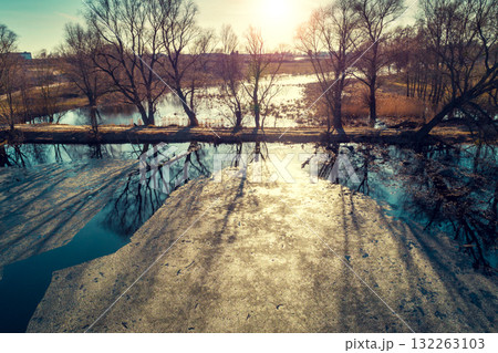 Aerial view of the countryside and frozen creek with a dam in the evening under sunset light. Beautiful natural landscape 132263103
