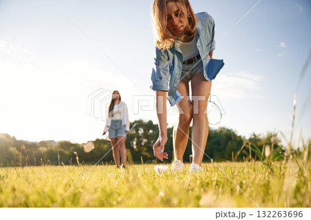 Picking up the fallen shuttlecock. Two women are having fun, with badminton rackets, on the field 132263696