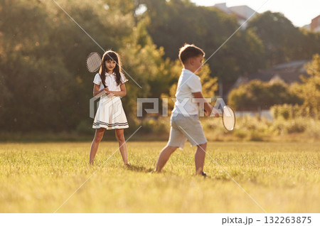 Rackets in hands, playing badminton. Happy kids are on the summer field 132263875