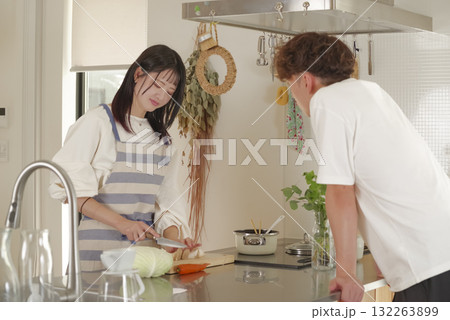 エプロン姿で料理する女性と会話を楽しむ男性 132263899
