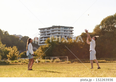 Side view. Man with woman are playing badminton on the field 132263936