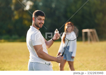 Weekend activities. Man with woman are playing badminton on the field Weekend activities. Man with woman are playing badminton on the field 132263940