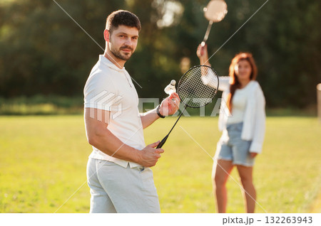 Weekend activities. Man with woman are playing badminton on the field 132263943
