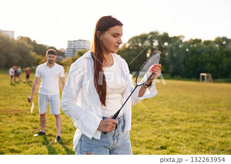 Taking a rest, standing. Man with woman are playing badminton on the field 132263954