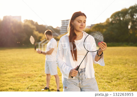 Taking a rest, standing. Man with woman are playing badminton on the field Taking a rest, standing. Man with woman are playing badminton on the field 132263955