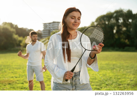 Taking a rest, standing. Man with woman are playing badminton on the field 132263956