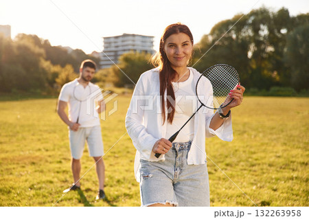 Taking a rest, standing. Man with woman are playing badminton on the field Taking a rest, standing. Man with woman are playing badminton on the field 132263958