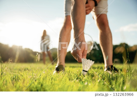 Guy is picking up the shuttlecock. Man with woman are playing badminton on the field Guy is picking up the shuttlecock. Man with woman are playing badminton on the field 132263966