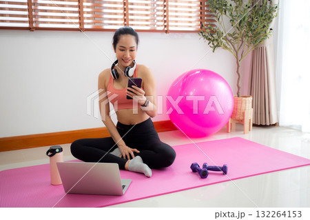 Young asian woman watching smartphone for practice yoga and workout in living room at home. Young asian woman watching smartphone for practice yoga and workout in living room at home. 132264153