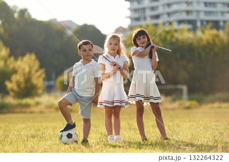 Soccer ball and badminton rackets. Happy kids are on the summer field Soccer ball and badminton rackets. Happy kids are on the summer field 132264322