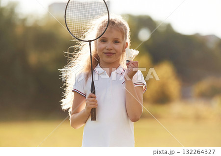 Cute little girl is with badminton racket on the field Cute little girl is with badminton racket on the field 132264327