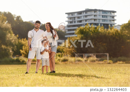 Father, mother and son are standing and holding badminton rackets. On the field Father, mother and son are standing and holding badminton rackets. On the field 132264403