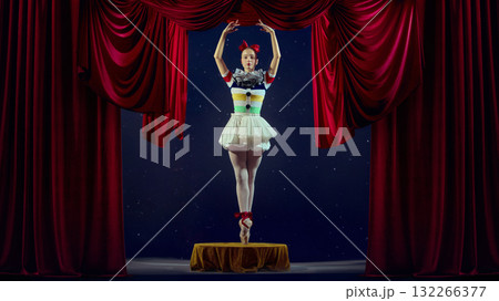 Center of attention. Ballerina standing on stage in theatrical light with red curtains. Center of attention. Ballerina standing on stage in theatrical light with red curtains. 132266377