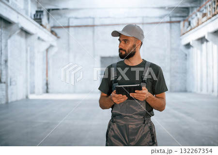 Black digital tablet in hands. Male worker is in the empty warehouse 132267354