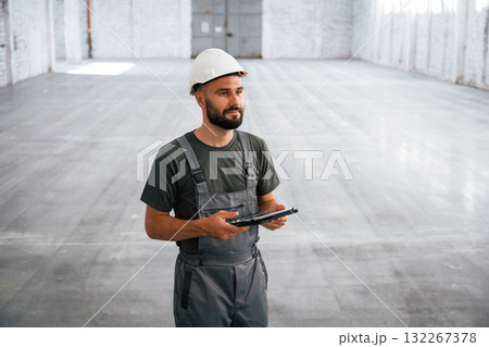 View from the front, with digital tablet in hands. Male worker is in the empty warehouse 132267378