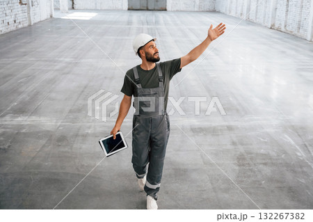 Showing the area by the hands. Male worker is in the empty warehouse Showing the area by the hands. Male worker is in the empty warehouse 132267382