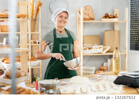 Female bkery cook whisks chicken eggs to make dough in bakery kitchen Female bkery cook whisks chicken eggs to make dough in bakery kitchen 132267812