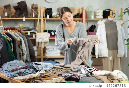 Young woman chooses sweater in clothing store Young woman chooses sweater in clothing store 132267818