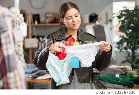 Female shopper selects panties in fashionable clothing boutique. Female shopper selects panties in fashionable clothing boutique. 132267836