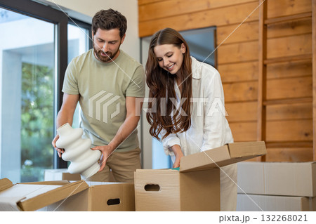 Excited couple unpacking boxes in their new home and feeling joyful Excited couple unpacking boxes in their new home and feeling joyful 132268021
