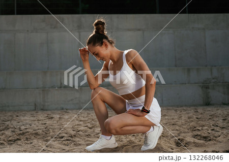 Sitting and thinking, popular pose. Young skinny fitness woman is outdoors Sitting and thinking, popular pose. Young skinny fitness woman is outdoors 132268046
