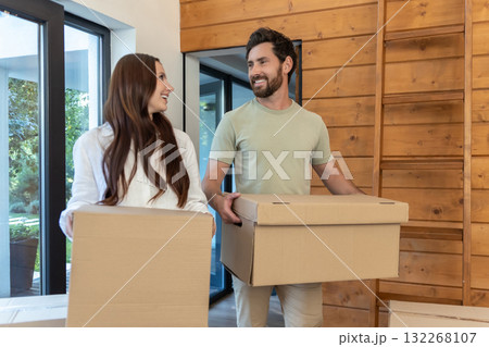Man and woman carrying boxes into a new accommodation and feeling excited Man and woman carrying boxes into a new accommodation and feeling excited 132268107