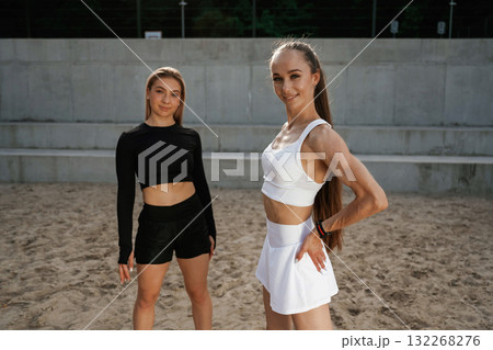 Standing and posing. Two sportive women are outdoors together Standing and posing. Two sportive women are outdoors together 132268276