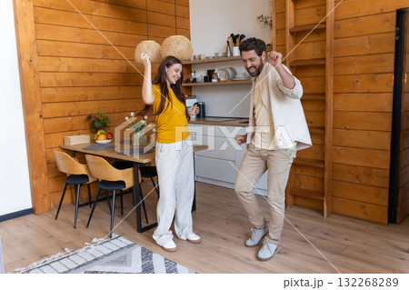 Cute couple feeling excited and dancing in the kitchen Cute couple feeling excited and dancing in the kitchen 132268289