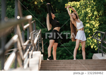 Getting ready, warm up exercises. Two sportive women are outdoors together 132268462