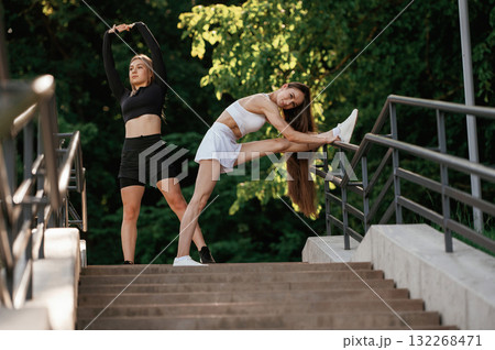 Getting ready, warm up exercises. Two sportive women are outdoors together 132268471