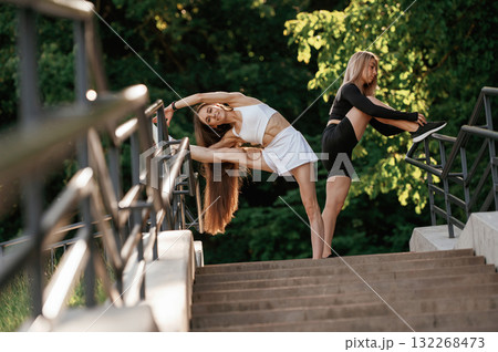 Railings and stairs. Two sportive women are outdoors together Railings and stairs. Two sportive women are outdoors together 132268473