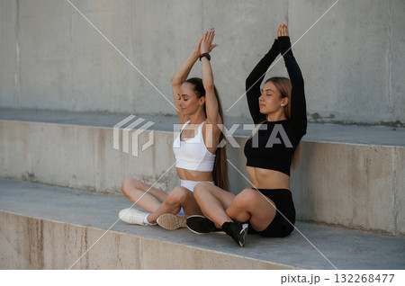 In lotus pose, yoga. Two sportive women are outdoors together In lotus pose, yoga. Two sportive women are outdoors together 132268477