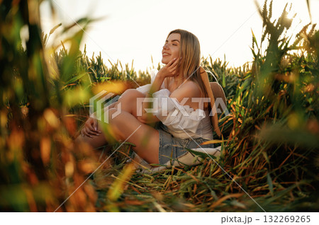 Smiling, feeling good. Beautiful woman is sitting on the ground in the agricultural field Smiling, feeling good. Beautiful woman is sitting on the ground in the agricultural field 132269265