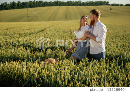 Summertime wellness, happiness. Lovely couple are on the green agricultural field together Summertime wellness, happiness. Lovely couple are on the green agricultural field together 132269404