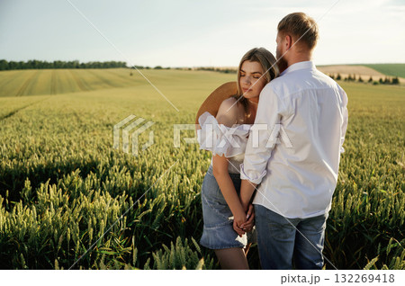 Non urban view, leisure. Lovely couple are on the green agricultural field together Non urban view, leisure. Lovely couple are on the green agricultural field together 132269418