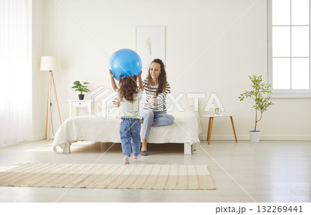 Loving young mother, babysitter and little child playing together with ball at home enjoying leisure Loving young mother, babysitter and little child playing together with ball at home enjoying leisure 132269441
