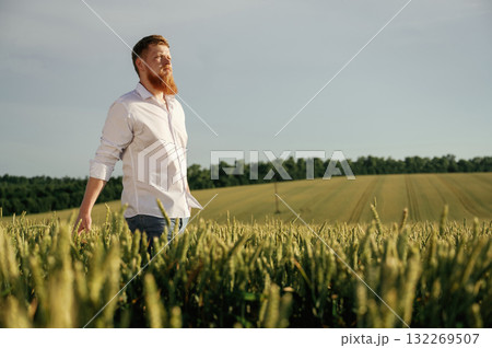 Having a walk. Man in white shirt is on the agricultural field 132269507