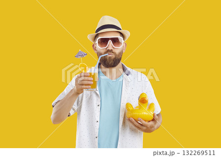 Funny bearded man in beach hat and sunglasses drinking cocktail on yellow background. 132269511