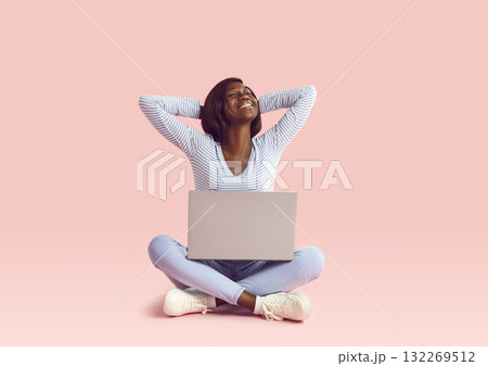 Young relaxed happy woman sitting with a laptop on studio pink background. Young relaxed happy woman sitting with a laptop on studio pink background. 132269512