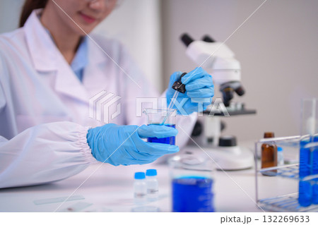 Asian woman scientist performs laboratory chemical experiment precise liquid handling modern research facility medical scientific discovery development 132269633