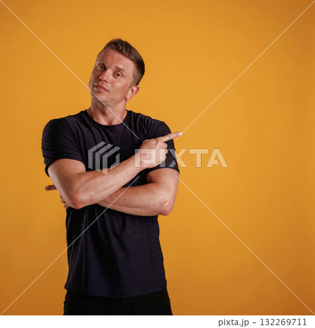 Showing to the side, pointing. Man is against background in the studio Showing to the side, pointing. Man is against background in the studio 132269711