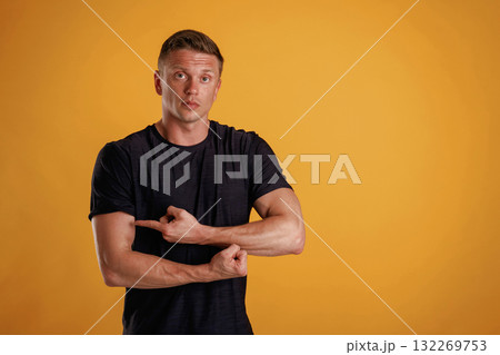 Biceps, pointing on it by finger. Man is against background in the studio Biceps, pointing on it by finger. Man is against background in the studio 132269753