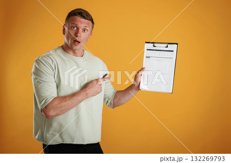 Results, data in the notepad, holding it. Man is against background in the studio Results, data in the notepad, holding it. Man is against background in the studio 132269793