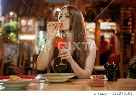 Red cocktail, drinking. Woman is in the restaurant with food and drink Red cocktail, drinking. Woman is in the restaurant with food and drink 132270102